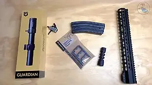 AR-15 upgrades to make your rifle run better – optic, trigger, muzzle brake, magazine follower, and handguard laid out on a workbench